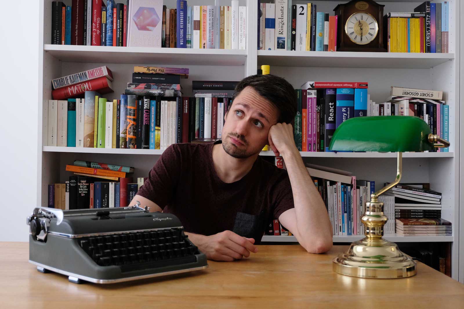 Foto von Fabian Navarro in nachdenklicher Pose vor einem Bücherregal