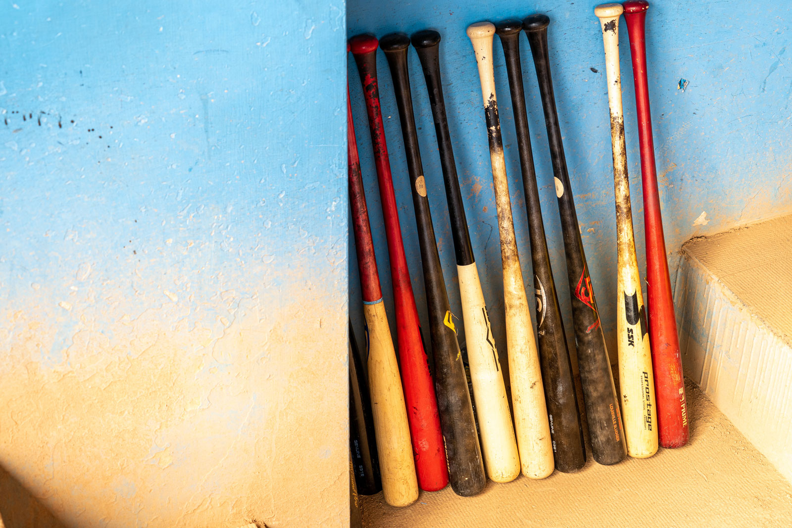 An einer Wand lehnen ein paar bunte Basballschläger