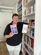 Das Bild zeigt Ina Kronenberger stehend vor einem Bücherregal.