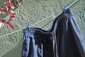 Eine blaue Badehose an einer Wäscheleine vor einer türkisen Wand
