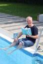 Will Gmehling sitzt mit seinem Buch "Freibad" am Beckenrand.