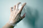 Eine Hand ist in Frischhaltefolie eingepackt und kratzt an der Wand.