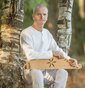 Edgars Lipors sitzt auf einem Baumstamm und hat ein Instrument auf dem Schoß