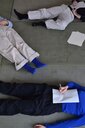 Auf diesem Bild liegen drei Personen schreibend auf dem Boden.