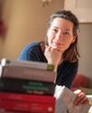 Das Portrait zeigt Linda Bulut vor einem Bücherstapel.