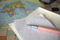 Ein Stift und Papier liegen auf einer Weltkarte.